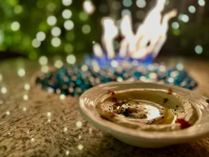 Firepit with greenry and lights in background. Bowl of hummus nearby. Zaytoon restaurant.