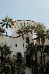 Courthouse in Santa Barbara California. Palm trees around a white spanish style building with blue sky.