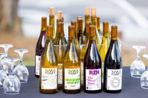 Wine bottles featuring RZN wines with upside down glassware on a table with a black cloth